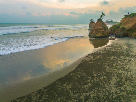 Aerial view of a sandy beach with rocky cliffs gentle waves and soft sunset light in Bali Bali Indonesia. Aerial view of a sandy beach with rocky cliffs gentle waves and soft sunset light in Bali Bali Indonesia.