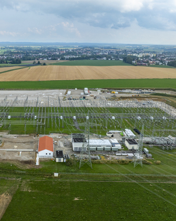 Aerial view of Umspannwerk Ottenhofen electrical substation with power lines and transformers surrounded by agricultural fields and the town of Ottenhofen Bayern Germany.