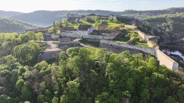 Aerial view of the Besancon Citadel with its historic stone walls and lush green forest under a bright morning sky in Besancon Bourgogne Franche Comte France. Aerial view of the Besancon Citadel with its historic stone walls and lush green forest under a bright morning sky in Besancon Bourgogne Franche Comte France.