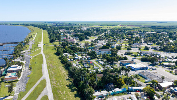 Aerial view of Pahokee along the shores of Lake Okeechobee featuring a marina residential areas lush palm trees and a clear blue sky in Pahokee Florida United States. Aerial view of Pahokee along the shores of Lake Okeechobee featuring a marina residential areas lush palm trees and a clear blue sky in Pahokee Florida United States.