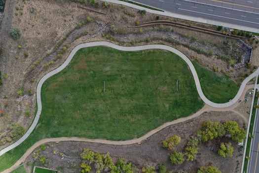 Aerial view of a green park with a winding walking path lush grass and surrounding trees in Golden Colorado United States.
