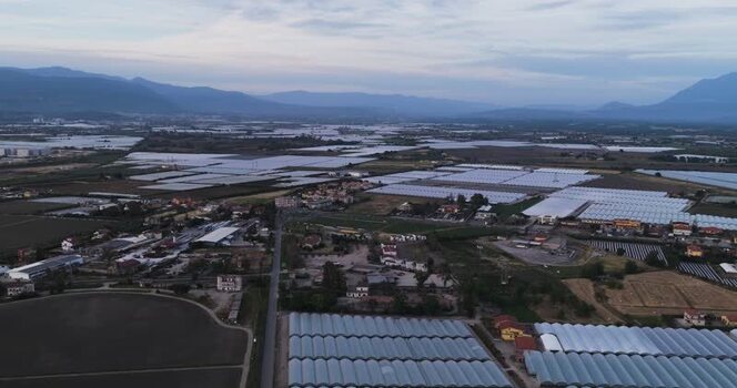 Aerial view of greenhouses and rural landscape in Italy.
