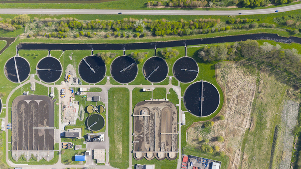 Aerial view of RWZI Geestmerambacht wastewater treatment plant with circular sedimentation tanks and aeration basins surrounded by green fields Netherlands. Aerial view of RWZI Geestmerambacht wastewater treatment plant with circular sedimentation tanks and aeration basins surrounded by green fields Netherlands.