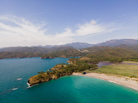 Aerial view of Karaot Beach with its turquoise waters rocky headland and surrounding green hills under a clear blue sky in Fethiye Mugla Turkiye. Aerial view of Karaot Beach with its turquoise waters rocky headland and surrounding green hills under a clear blue sky in Fethiye Mugla Turkiye.