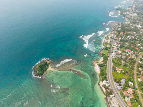 Aerial view of Devil s Rock island surrounded by turquoise waters and a coastal road in Ahangama Southern Province Sri Lanka. Aerial view of Devil s Rock island surrounded by turquoise waters and a coastal road in Ahangama Southern Province Sri Lanka.