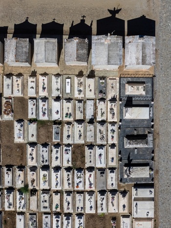 Aerial view of a cemetery with rows of white stone tombs crosses and long shadows cast by monuments in Evora Evora District Portugal. Aerial view of a cemetery with rows of white stone tombs crosses and long shadows cast by monuments in Evora Evora District Portugal.