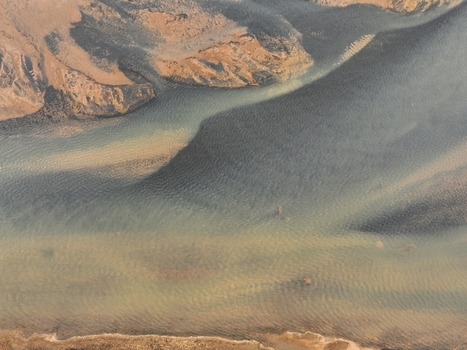 Aerial view of a glacial river with sediment rich water flowing through a rugged landscape in Selfoss Sveitarfelagid Arborg Iceland. Aerial view of a glacial river with sediment rich water flowing through a rugged landscape in Selfoss Sveitarfelagid Arborg Iceland.