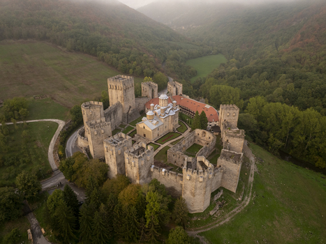 Aerial view of Manasija Monastery a historic fortified medieval Serbian Orthodox monastery with stone walls and towers surrounded by lush green hills in Despotovac Pomoravski okrug Serbia.