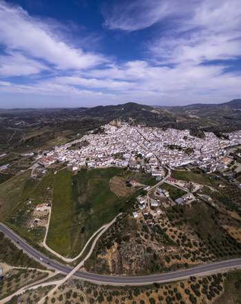 Aerial view of the historic white town of Olvera with its castle perched on a hilltop surrounded by rolling hills and olive groves in Olvera Andalusia Spain. Aerial view of the historic white town of Olvera with its castle perched on a hilltop surrounded by rolling hills and olive groves in Olvera Andalusia Spain.
