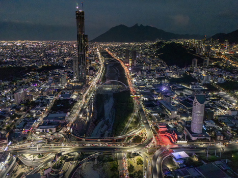 Aerial view of the illuminated Monterrey skyline at night featuring the Santa Catarina River busy highway interchanges and the silhouette of Cerro de la Silla Monterrey Nuevo Leon Mexico. Aerial view of the illuminated Monterrey skyline at night featuring the Santa Catarina River busy highway interchanges and the silhouette of Cerro de la Silla Monterrey Nuevo Leon Mexico.