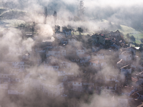 Aerial view of the historic village of Avo shrouded in thick morning mist with white houses and terracotta roofs nestled among green hills Oliveira do Hospital Coimbra District Portugal.