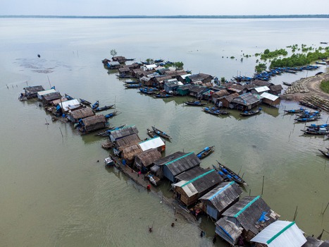 Aerial view of Kalabagi village with stilt houses and numerous wooden fishing boats moored along the riverbank in Khulna District Khulna Division Bangladesh.