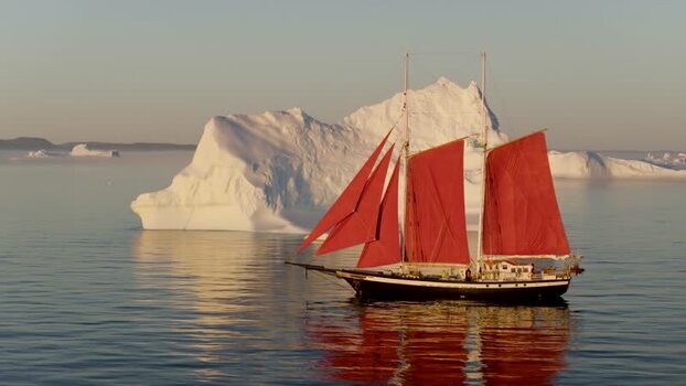 Aerial view of sailboat with red sails near iceberg Greenland. Aerial view of sailboat with red sails near iceberg Greenland.
