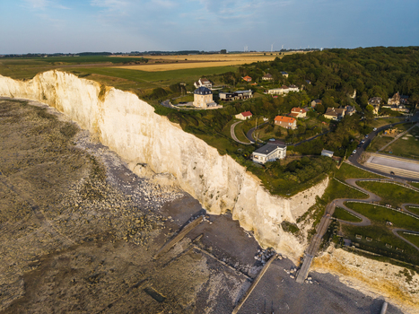 Aerial view of the Beach of the Bois de Cise with its dramatic white chalk cliffs lush green hills and coastal houses in Ault Hauts de France France.