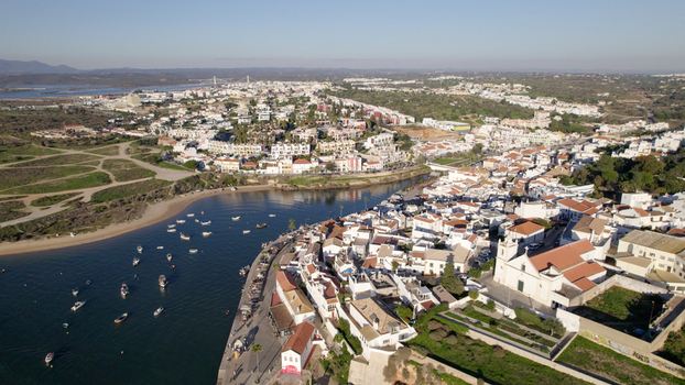Aerial view of the historic village of Ferragudo with its white washed houses church and river estuary filled with small fishing boats in Ferragudo Faro District Portugal.
