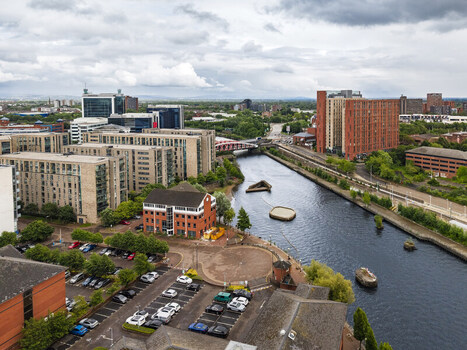 Aerial view of MediaCityUK and the Manchester Ship Canal surrounded by modern urban architecture and green spaces in Salford England United Kingdom. Aerial view of MediaCityUK and the Manchester Ship Canal surrounded by modern urban architecture and green spaces in Salford England United Kingdom.
