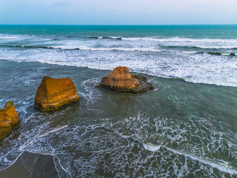 Aerial view of rocky sea stacks rising from the ocean waves along the coastline of Bali Indonesia. Aerial view of rocky sea stacks rising from the ocean waves along the coastline of Bali Indonesia.