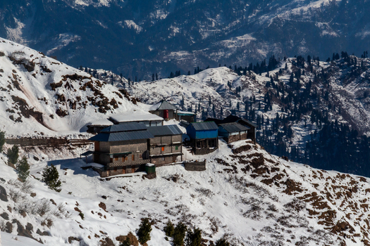 View of snow dusted dwellings nestle on a mountain ridge where trees stand sentinel against the backdrop of majestic snow capped peaks Haveli Azad Kashmir Azad Kashmir Pakistan.