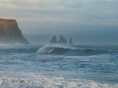 Aerial view of the dramatic sea stacks of Reynisdrangar rising from the Atlantic Ocean near the cliffs of Dyrholaey with powerful waves crashing in Myrdalshreppur Iceland. Aerial view of the dramatic sea stacks of Reynisdrangar rising from the Atlantic Ocean near the cliffs of Dyrholaey with powerful waves crashing in Myrdalshreppur Iceland.
