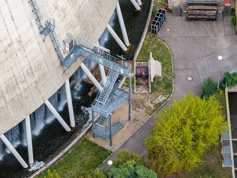 Aerial view of the Heizkraftwerk Reuter West cooling tower with water cascading down the base metal staircases and surrounding greenery in Berlin Berlin Germany.