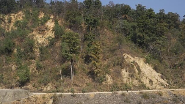 View of a forested hillside with erosion and a road Nepal.