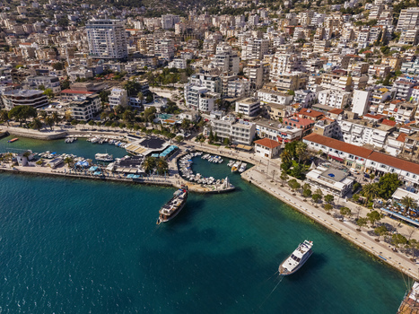 Aerial view of the coastal city of Saranda with its harbor docked boats turquoise water and dense urban architecture in Saranda Vlore County Albania. Aerial view of the coastal city of Saranda with its harbor docked boats turquoise water and dense urban architecture in Saranda Vlore County Albania.