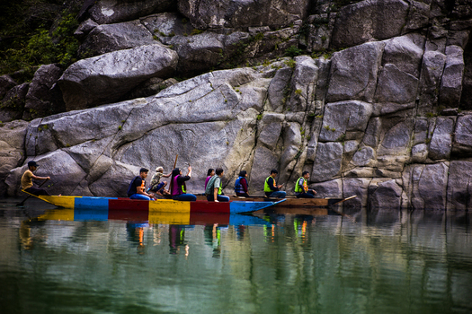 Meghalaya India 31 March 2023 View of people in colorful wooden boats navigating the calm river waters beneath towering rocky cliffs. Meghalaya India 31 March 2023 View of people in colorful wooden boats navigating the calm river waters beneath towering rocky cliffs.