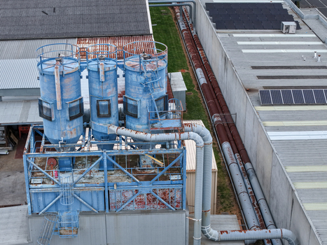 Melbourne VIC Australia 25 September 2026 Aerial view of an industrial facility featuring weathered blue silos metal piping and solar panels on the roof of a factory building.