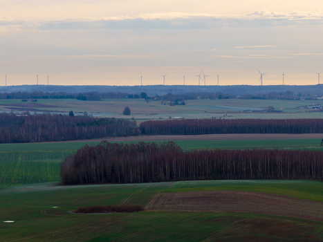 Aerial view of rolling agricultural fields and dense forest patches with wind turbines on the horizon under a soft sky Nemencine Vilnius County Lithuania. Aerial view of rolling agricultural fields and dense forest patches with wind turbines on the horizon under a soft sky Nemencine Vilnius County Lithuania.