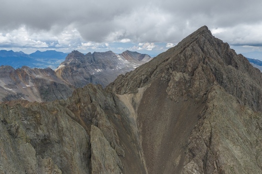 Aerial view of Mount Sneffels in the San Juan Mountains with rugged rocky peaks and steep slopes under a cloudy sky in Ouray County Colorado United States. Aerial view of Mount Sneffels in the San Juan Mountains with rugged rocky peaks and steep slopes under a cloudy sky in Ouray County Colorado United States.
