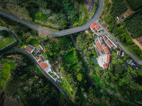 Aerial view of terracotta rooftops nestled amidst verdant landscapes bisected by winding roads creating a tapestry of color and texture Agua de Alto Azores Portugal.