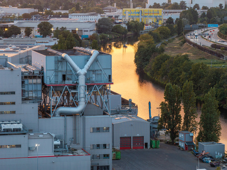 Aerial view of the BTB Blockheizkraftwerks facility featuring industrial architecture large ventilation pipes and a river reflecting golden sunset light Berlin Berlin Germany. Aerial view of the BTB Blockheizkraftwerks facility featuring industrial architecture large ventilation pipes and a river reflecting golden sunset light Berlin Berlin Germany.