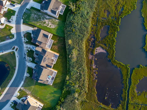 Ocean City Maryland United States 28 July 2019 Aerial view of a residential neighborhood bordering a marshland area with green lawns houses and a curved road.