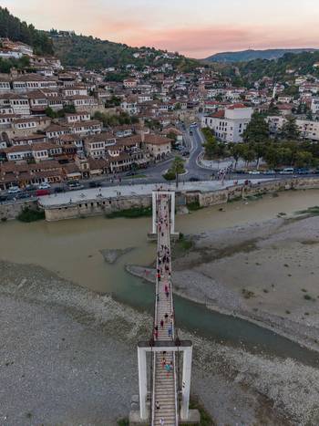Aerial view of the historic town of Berat featuring the pedestrian suspension bridge over the Osum River and traditional Ottoman style houses in Berat Berat County Albania.