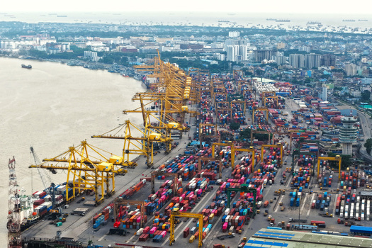 Aerial view of Chattogram Port with numerous shipping containers yellow gantry cranes and cargo ships along the Karnaphuli River in Chittagong Chittagong Division Bangladesh.