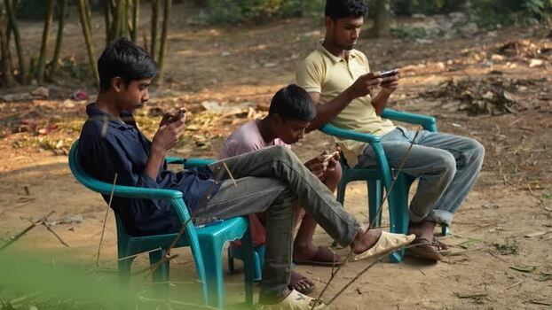 View of young men using smartphones outdoors in Bogura Bangladesh. View of young men using smartphones outdoors in Bogura Bangladesh.