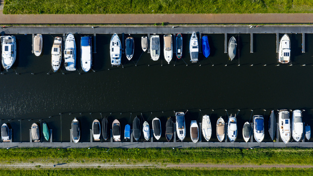 Aerial view of boats moored at the Oosterdel marina with parallel docks and green banks in Broek op Langedijk Noord Holland Netherlands. Aerial view of boats moored at the Oosterdel marina with parallel docks and green banks in Broek op Langedijk Noord Holland Netherlands.