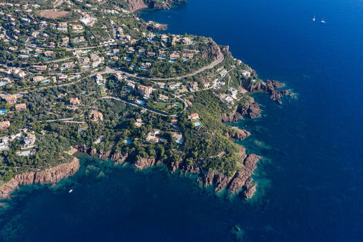 Aerial view of Le Trayas featuring red rock cliffs Mediterranean sea hillside villas and winding roads in Saint Raphael Provence Alpes Cote d Azur France. Aerial view of Le Trayas featuring red rock cliffs Mediterranean sea hillside villas and winding roads in Saint Raphael Provence Alpes Cote d Azur France.
