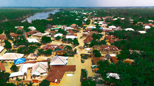 Aerial view of the village of Abua featuring traditional houses with metal roofs a central dirt road and surrounding lush tropical vegetation in Abua Rivers Nigeria. Aerial view of the village of Abua featuring traditional houses with metal roofs a central dirt road and surrounding lush tropical vegetation in Abua Rivers Nigeria.