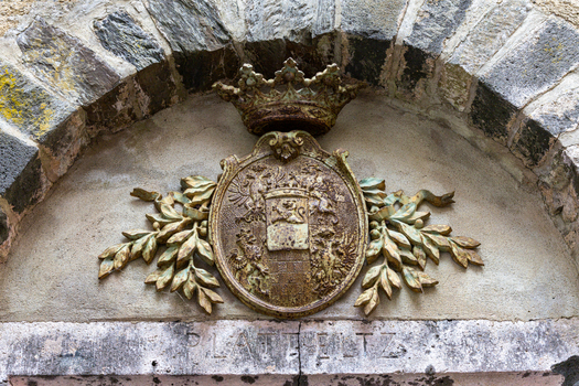 View of the historic coat of arms of Eltz Castle featuring a weathered heraldic shield with a crown and leafy branches under a stone archway in Wierschem Rhineland Palatinate Germany.