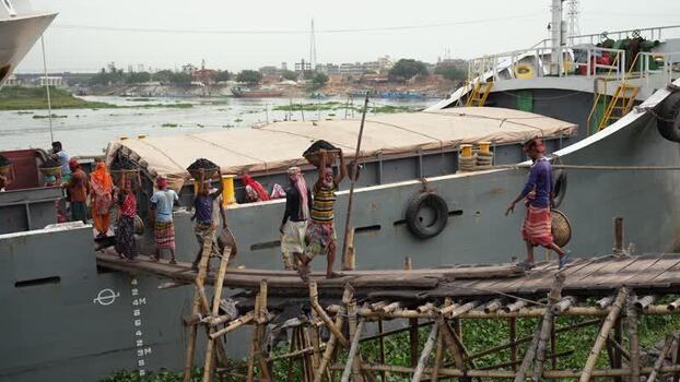 View of workers unloading cargo from a ship in Aminbazar Bangladesh.