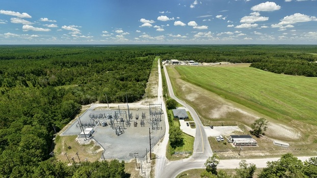 Aerial view of the Putnam County Central Landfill featuring a power substation adjacent road and expansive green fields surrounded by dense forest in Palatka Florida United States.