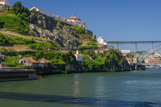 Aerial view of the Douro River winding past the Vila Nova de Gaia cliffs and Dom Luís I Bridge under a bright sky Porto Porto District Portugal. Aerial view of the Douro River winding past the Vila Nova de Gaia cliffs and Dom Luís I Bridge under a bright sky Porto Porto District Portugal.