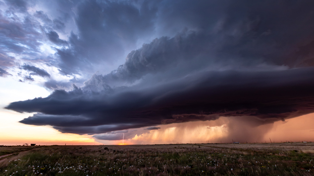 View of a dramatic supercell thunderstorm with a lightning strike over a vast prairie landscape during sunset in Oklahoma City Oklahoma United States.