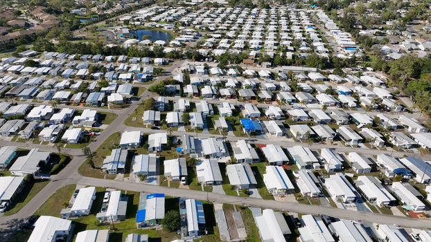 Aerial view of a dense mobile home park with rows of white rooftops paved streets and a small pond in Bradenton Florida United States.