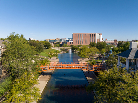 Aerial view of the Central Canal with its orange pedestrian bridge a fountain and surrounding lush trees in downtown Indianapolis Indiana United States. Aerial view of the Central Canal with its orange pedestrian bridge a fountain and surrounding lush trees in downtown Indianapolis Indiana United States.