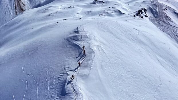 Aerial view of skiers climbing a snowy mountain in Austria.