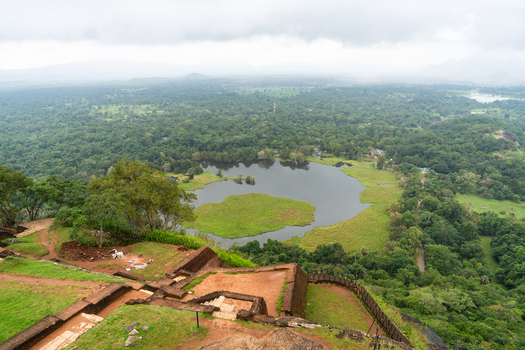View of the ancient ruins and lush jungle landscape with a circular lake from the top of Lion Rock in Sigiriya Central Province Sri Lanka. View of the ancient ruins and lush jungle landscape with a circular lake from the top of Lion Rock in Sigiriya Central Province Sri Lanka.