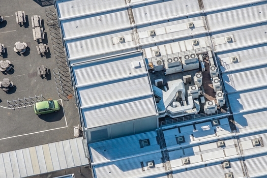 Aerial view of the Data Center at Oxford University featuring a corrugated metal roof with industrial HVAC units adjacent to a parking area in Oxford England United Kingdom. Aerial view of the Data Center at Oxford University featuring a corrugated metal roof with industrial HVAC units adjacent to a parking area in Oxford England United Kingdom.