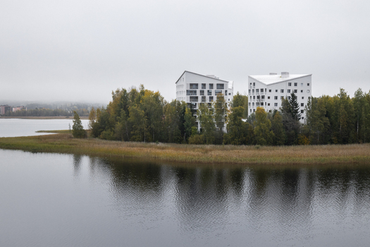 View of modern white apartment buildings situated on a forested lakeshore under a cloudy sky in Jyvaskyla Central Finland Finland.